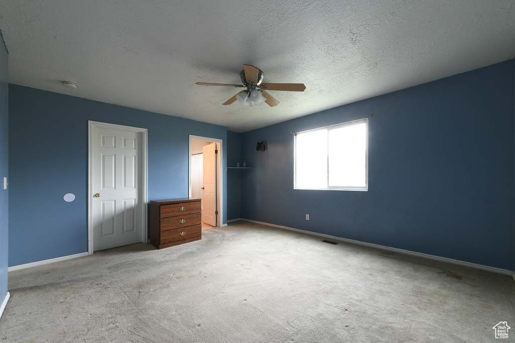 Unfurnished bedroom with light colored carpet, a textured ceiling, and ceiling fan
