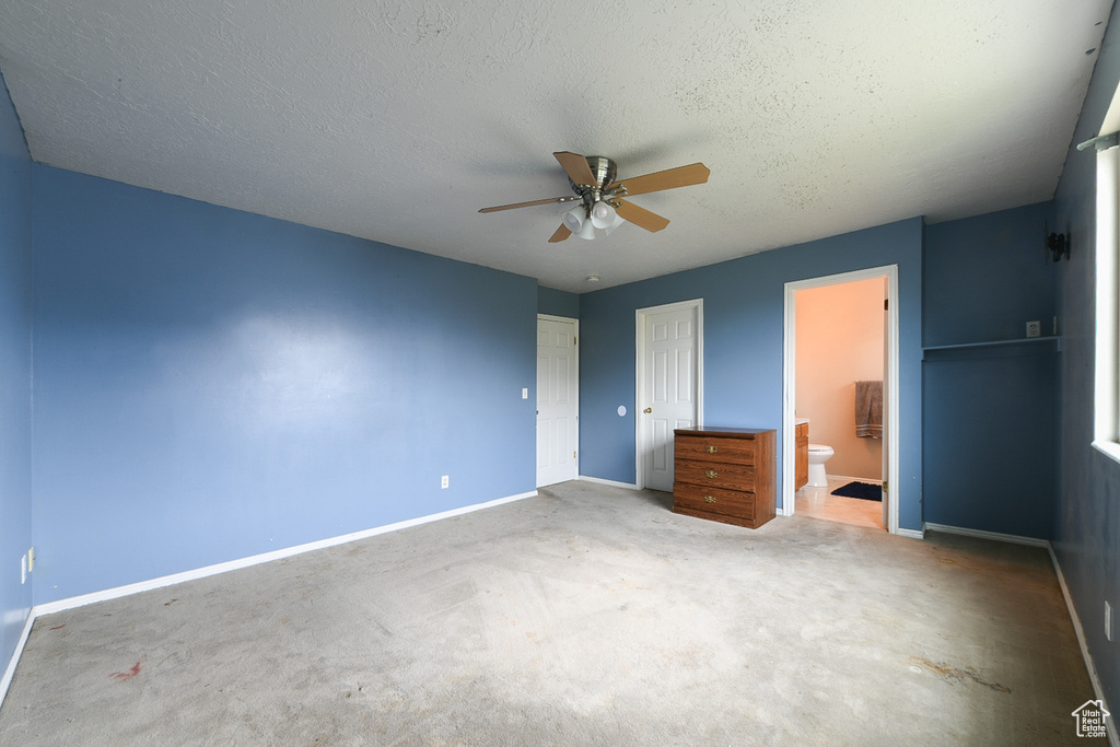 Unfurnished bedroom with carpet, connected bathroom, ceiling fan, and a textured ceiling