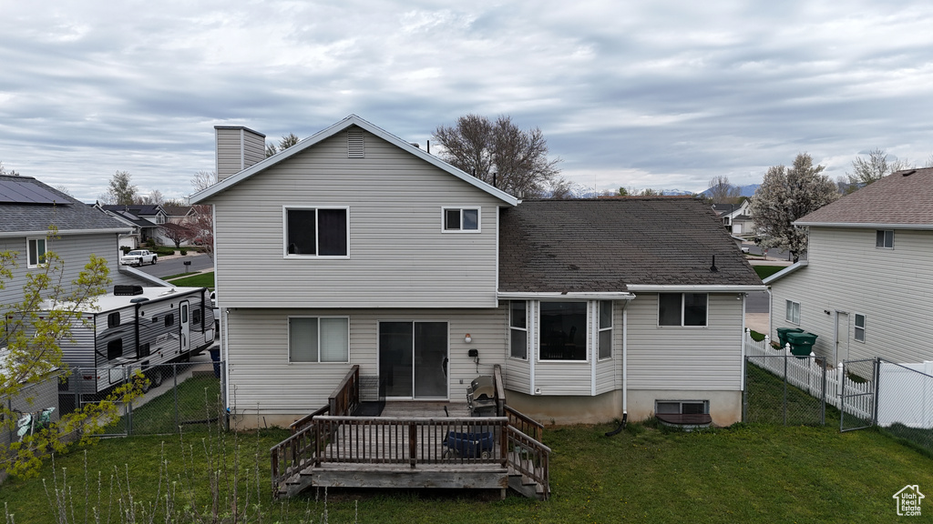 Back of property with a wooden deck and a lawn