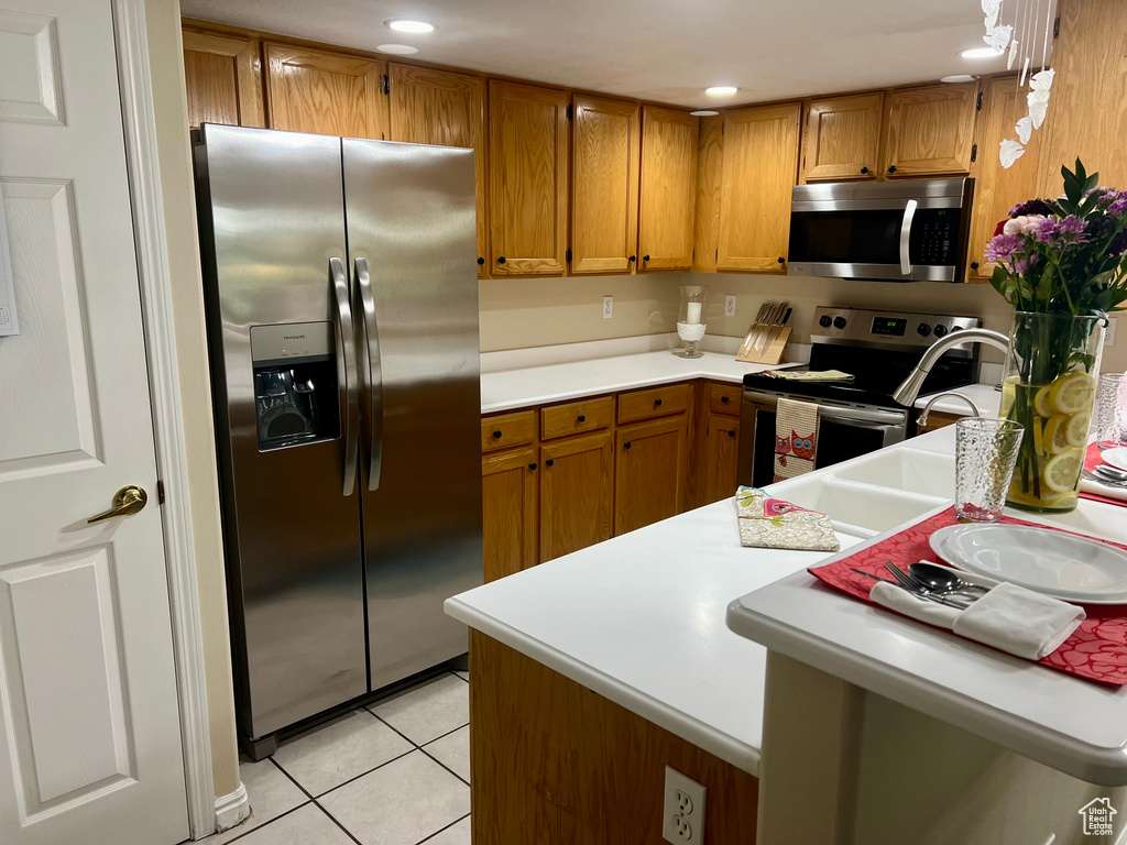 Kitchen featuring stainless steel appliances, kitchen peninsula, and light tile floors