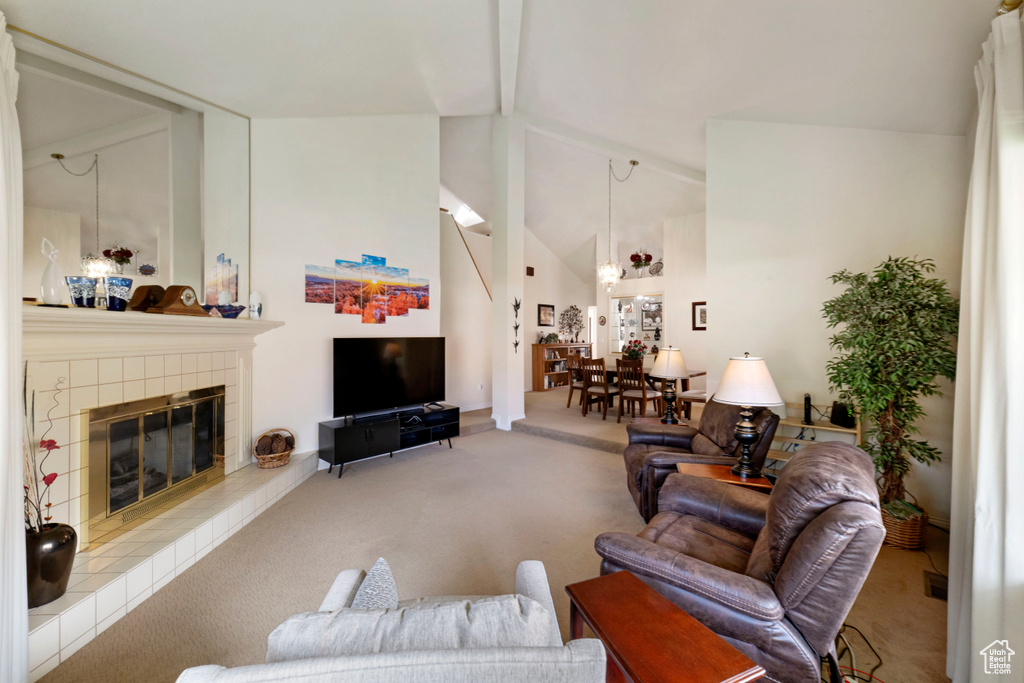 Carpeted living room featuring high vaulted ceiling, beamed ceiling, and a fireplace