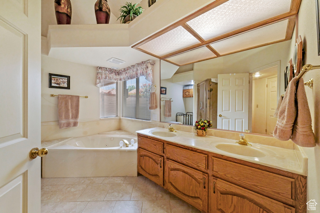 Bathroom with double sink vanity, a bathtub, and tile floors