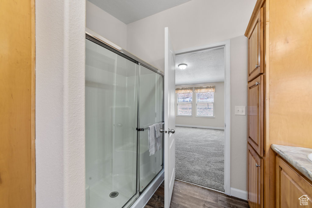 Bathroom featuring hardwood / wood-style floors, an enclosed shower, and vanity