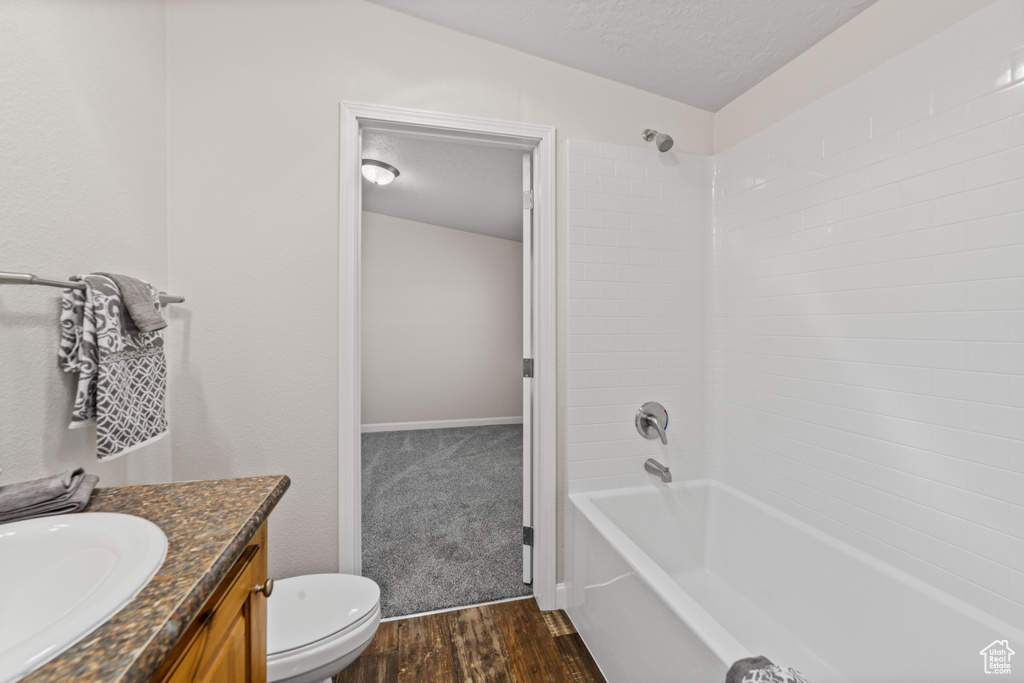 Full bathroom featuring a textured ceiling, washtub / shower combination, toilet, vanity, and hardwood / wood-style flooring