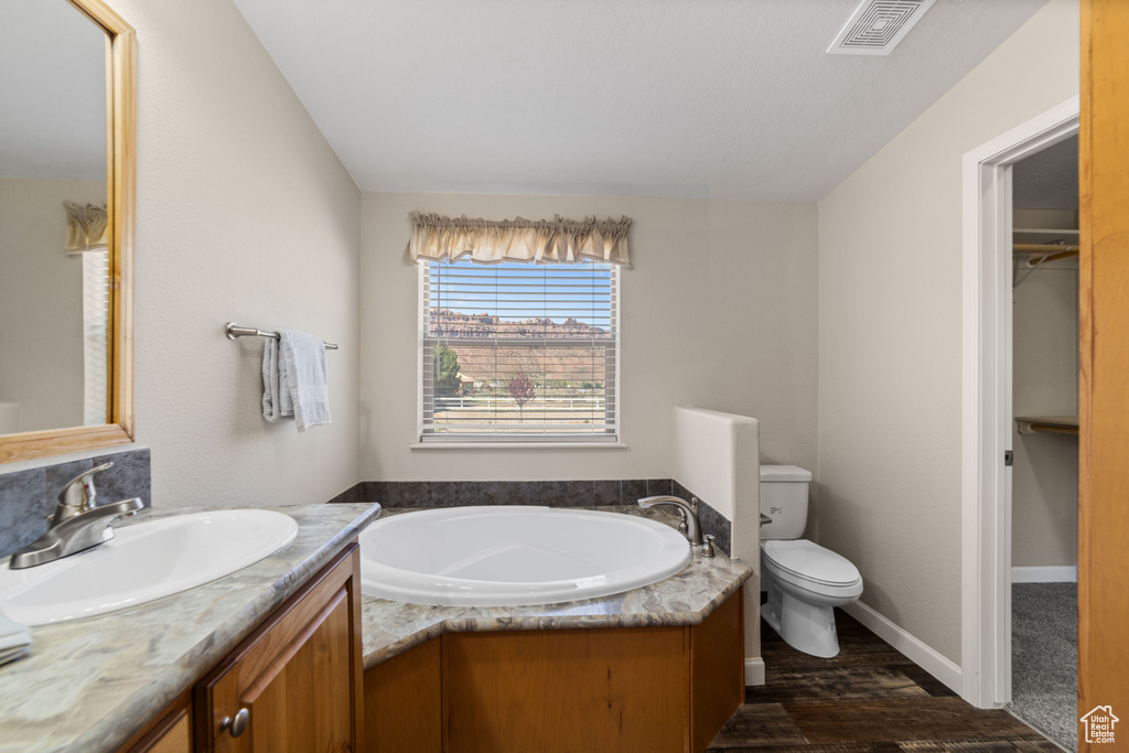 Bathroom featuring hardwood / wood-style floors, vanity, toilet, and a washtub