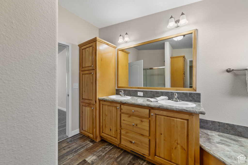 Bathroom featuring wood-type flooring, large vanity, and dual sinks