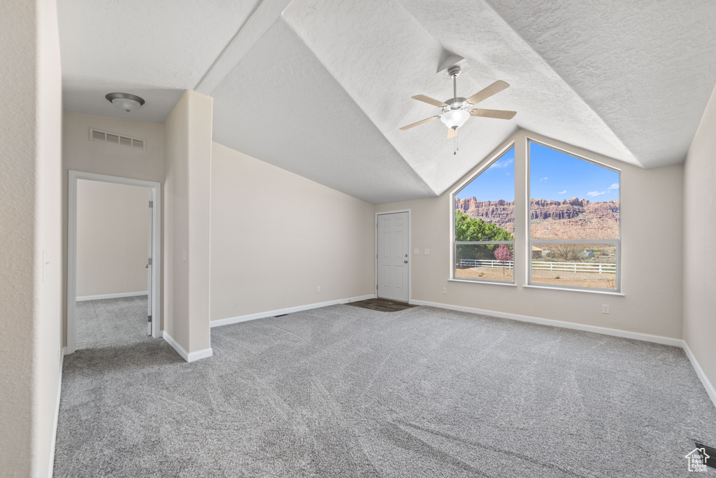 Bonus room with ceiling fan, dark carpet, vaulted ceiling, and a textured ceiling