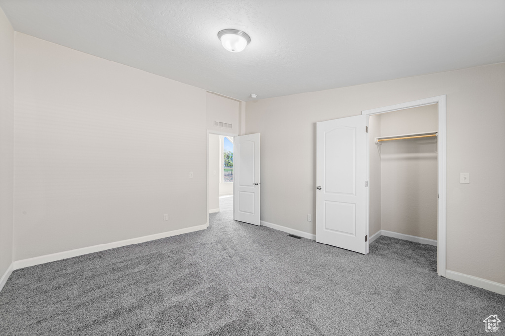 Unfurnished bedroom with light carpet, a closet, and a walk in closet