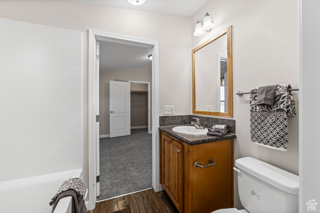 Full bathroom featuring vaulted ceiling, toilet, vanity, washtub / shower combination, and hardwood / wood-style floors