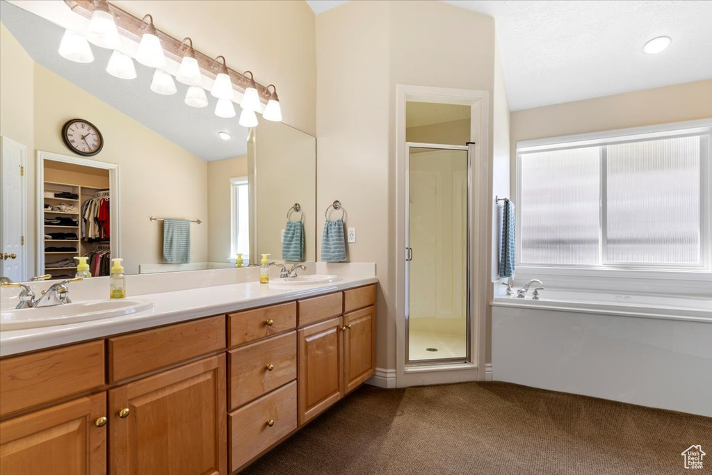 Bathroom with vaulted ceiling, dual bowl vanity, and plus walk in shower
