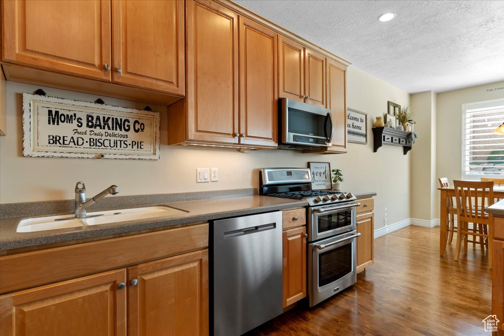 Kitchen featuring appliances with stainless steel finishes, dark hardwood / wood-style flooring, a textured ceiling, and sink