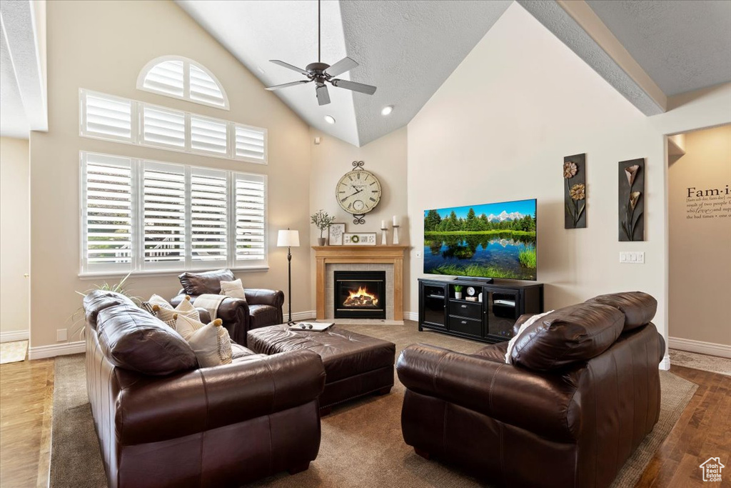Living room with ceiling fan, high vaulted ceiling, dark wood-type flooring, and a textured ceiling