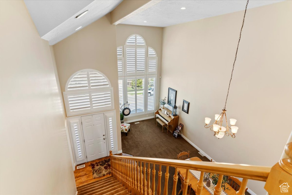 Entrance foyer featuring high vaulted ceiling, a notable chandelier, and dark hardwood / wood-style flooring