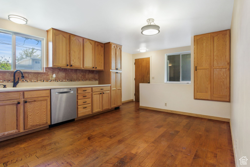 Kitchen with sink, dishwasher, backsplash, and dark wood-type flooring