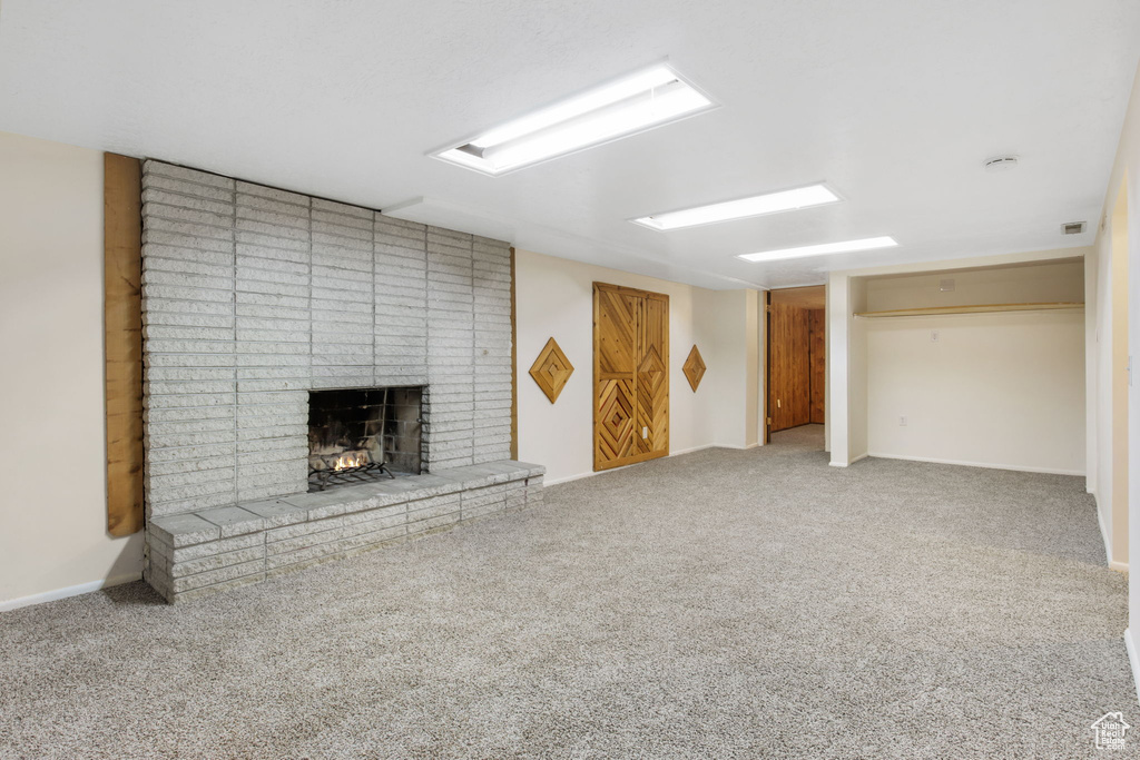 Basement with a fireplace and light carpet