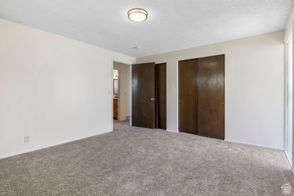 Unfurnished bedroom featuring multiple closets, a textured ceiling, and carpet