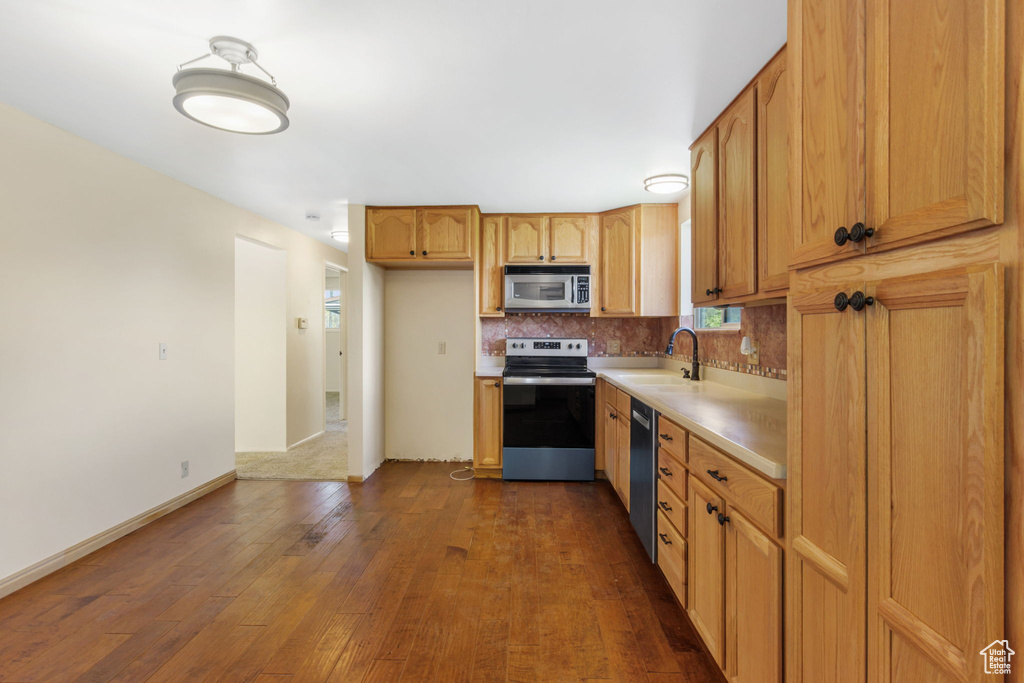 Kitchen featuring tasteful backsplash, stainless steel appliances, dark hardwood / wood-style floors, and sink