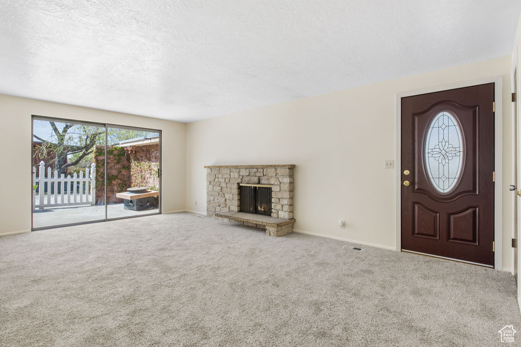 Entrance foyer with a fireplace, a textured ceiling, and carpet flooring