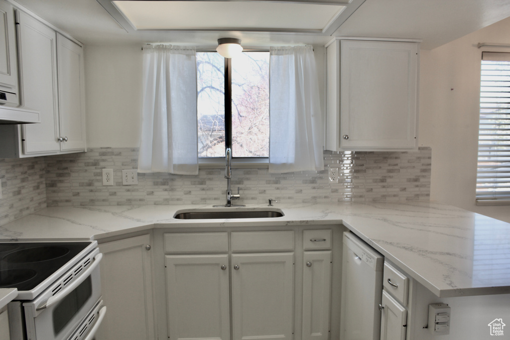 Kitchen featuring white cabinets, sink, light stone counters, tasteful backsplash, and dishwasher