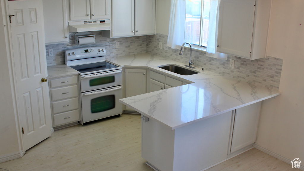 Kitchen with premium range hood, sink, white cabinets, and range with two ovens