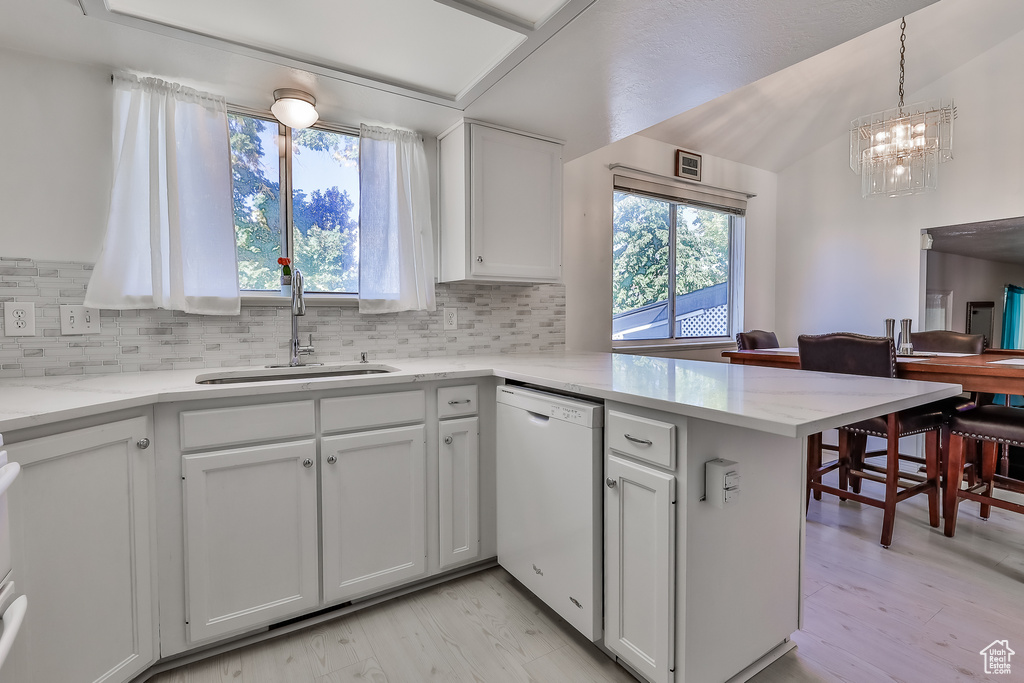 Kitchen featuring white cabinets, tasteful backsplash, light hardwood / wood-style floors, and dishwasher