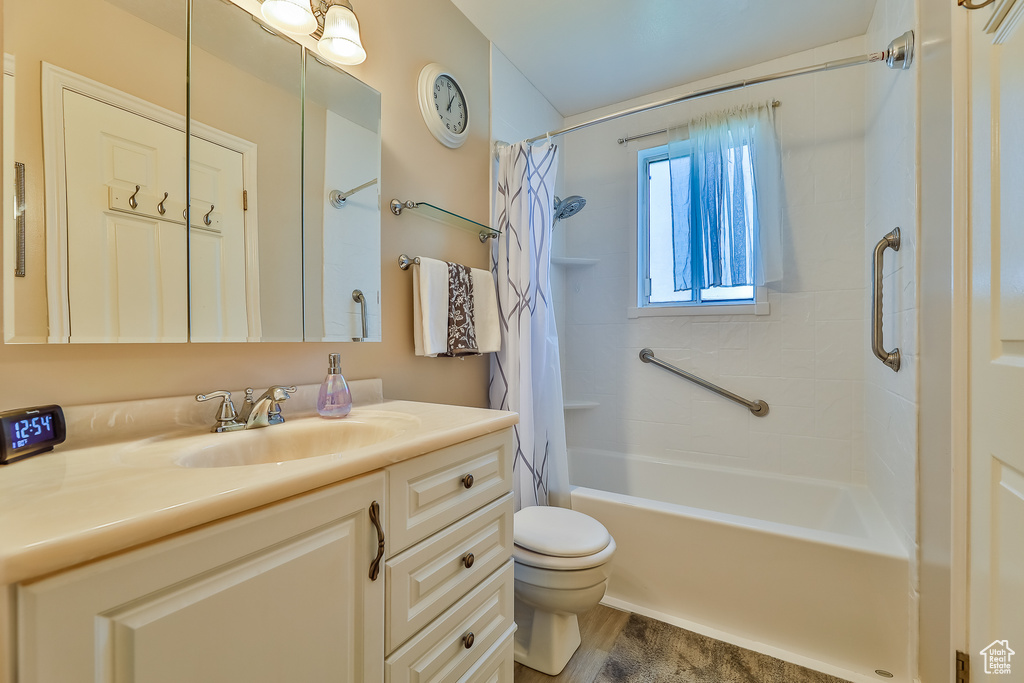 Full bathroom with shower / bath combo, toilet, oversized vanity, and hardwood / wood-style floors