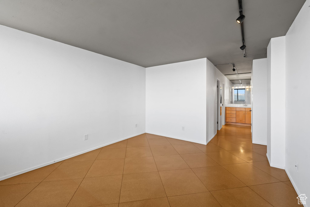 Unfurnished room with track lighting and light tile floors