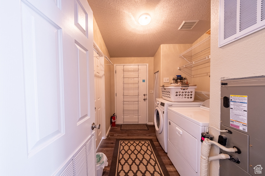 Clothes washing area featuring washer and clothes dryer, dark hardwood / wood-style floors, and a textured ceiling