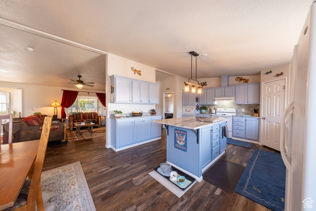 Kitchen with a center island, a kitchen breakfast bar, decorative light fixtures, dark wood-type flooring, and ceiling fan