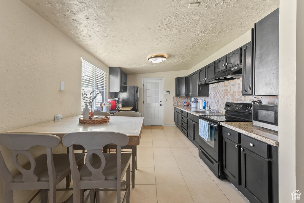 Kitchen with black appliances, a textured ceiling, tasteful backsplash, sink, and light tile floors