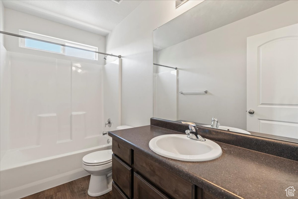 Full bathroom with wood-type flooring, shower / tub combination, vanity, and toilet