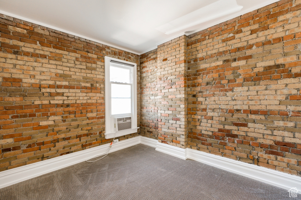 Spare room featuring brick wall and carpet flooring