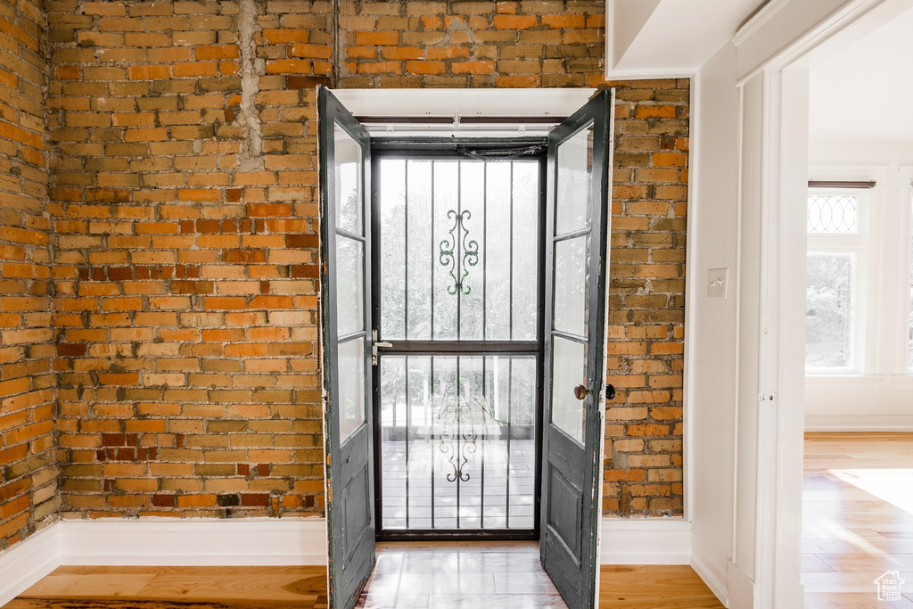 Doorway featuring light hardwood / wood-style floors and brick wall