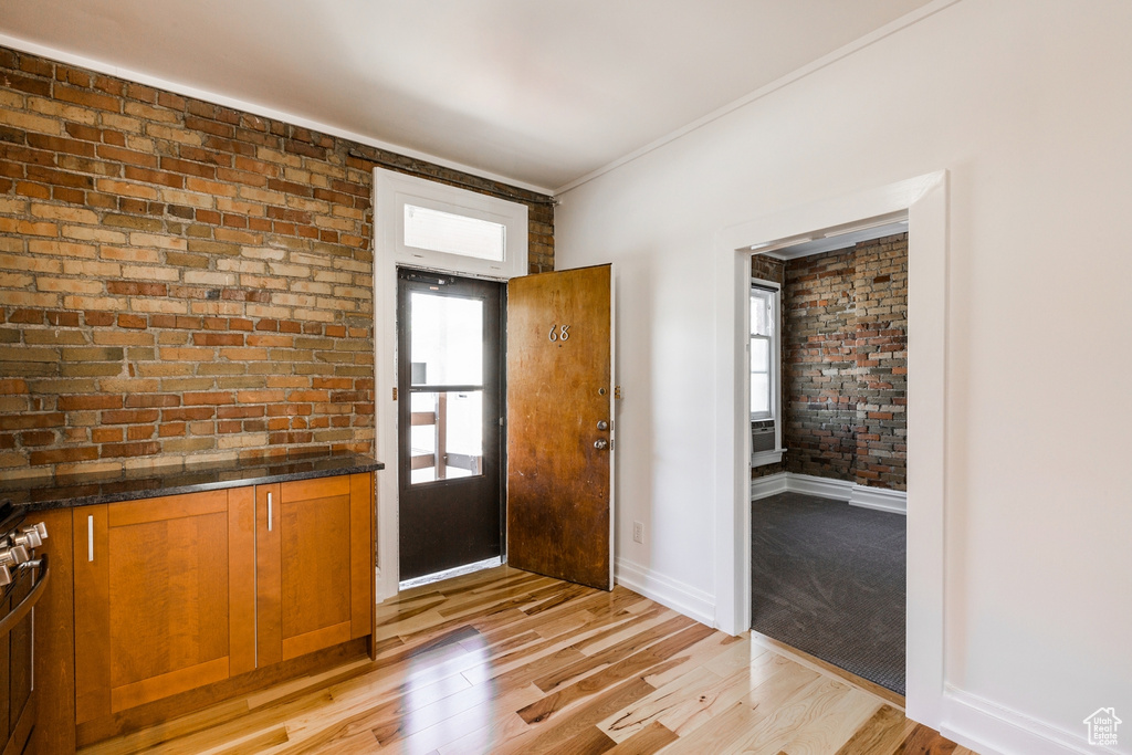 Foyer with brick wall and light hardwood / wood-style flooring