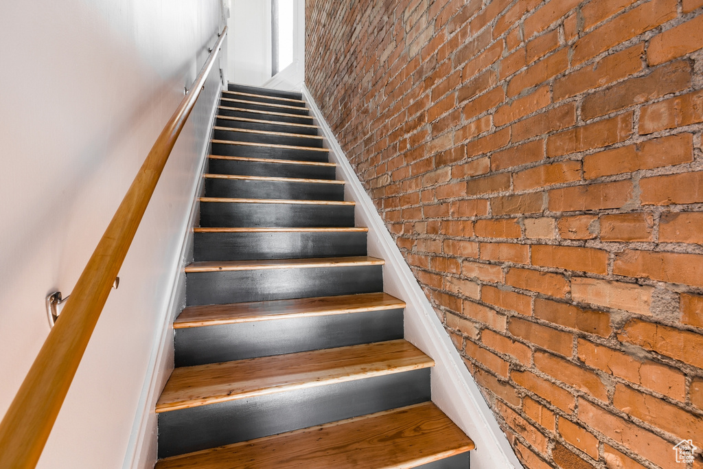 Staircase featuring brick wall