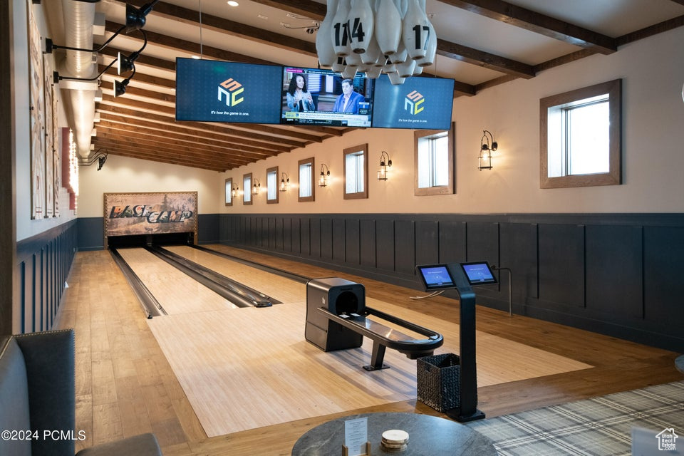 Rec room featuring lofted ceiling with beams, light hardwood / wood-style floors, and a bowling alley