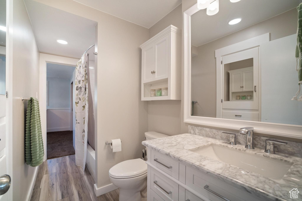 Full bathroom with shower / tub combo, hardwood / wood-style flooring, toilet, and large vanity