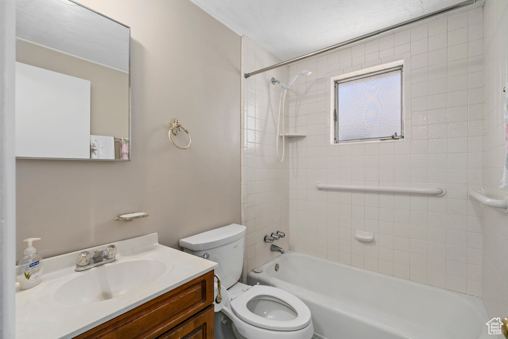 Full bathroom with vanity with extensive cabinet space, toilet, and tiled shower / bath