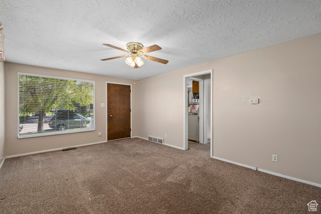 Unfurnished room with dark carpet, ceiling fan, and a textured ceiling