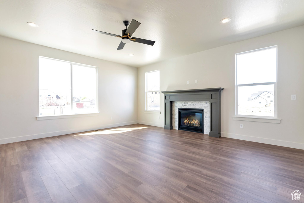Unfurnished living room with ceiling fan, a wealth of natural light, and dark hardwood / wood-style flooring