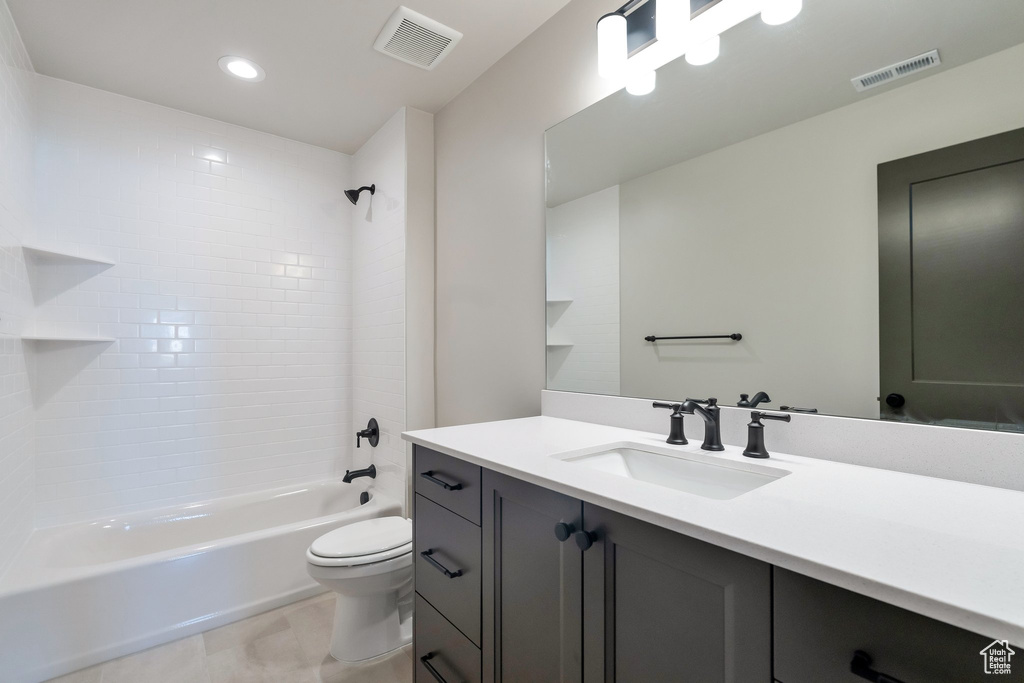 Full bathroom with tile floors, tiled shower / bath, vanity with extensive cabinet space, and toilet