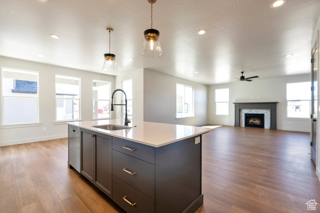 Kitchen featuring pendant lighting, dishwasher, a kitchen island with sink, sink, and dark hardwood / wood-style flooring