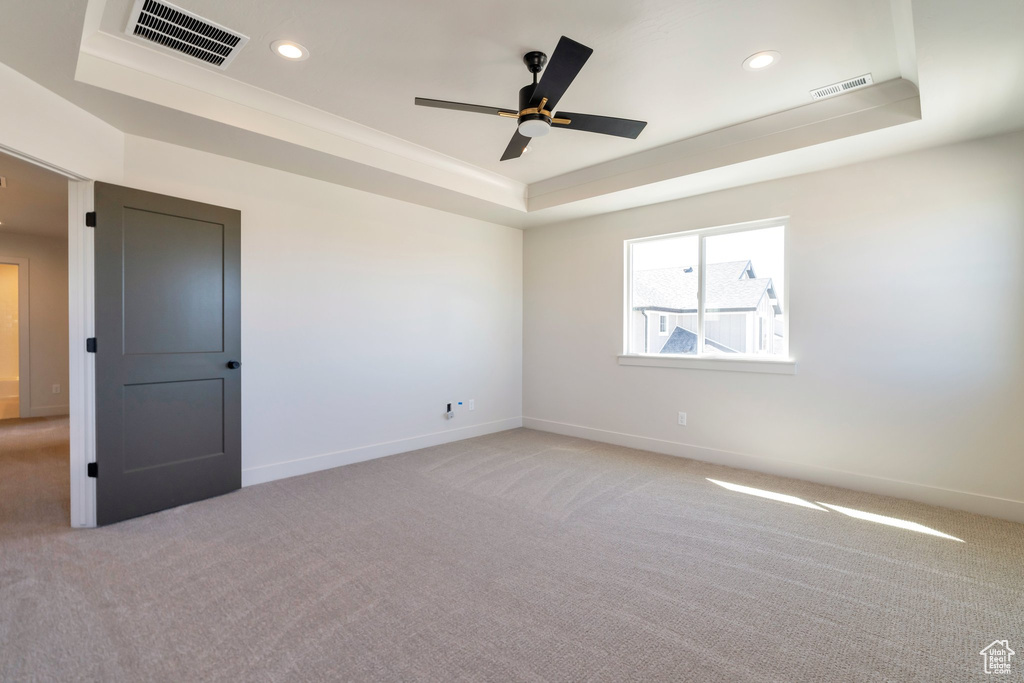 Empty room featuring light carpet and a tray ceiling