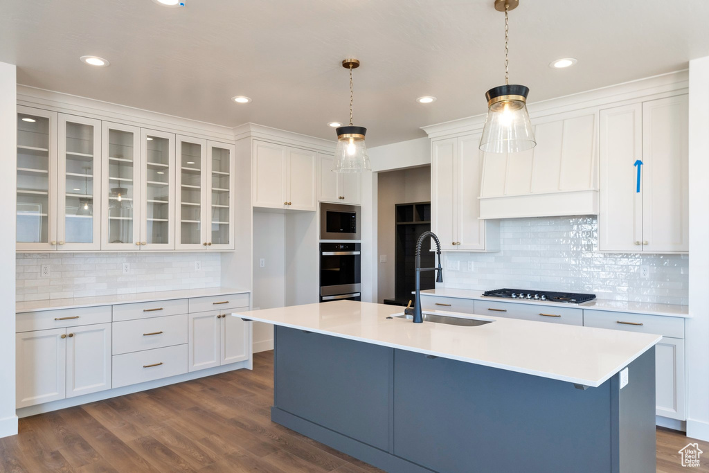 Kitchen with stainless steel appliances, white cabinetry, sink, and decorative light fixtures
