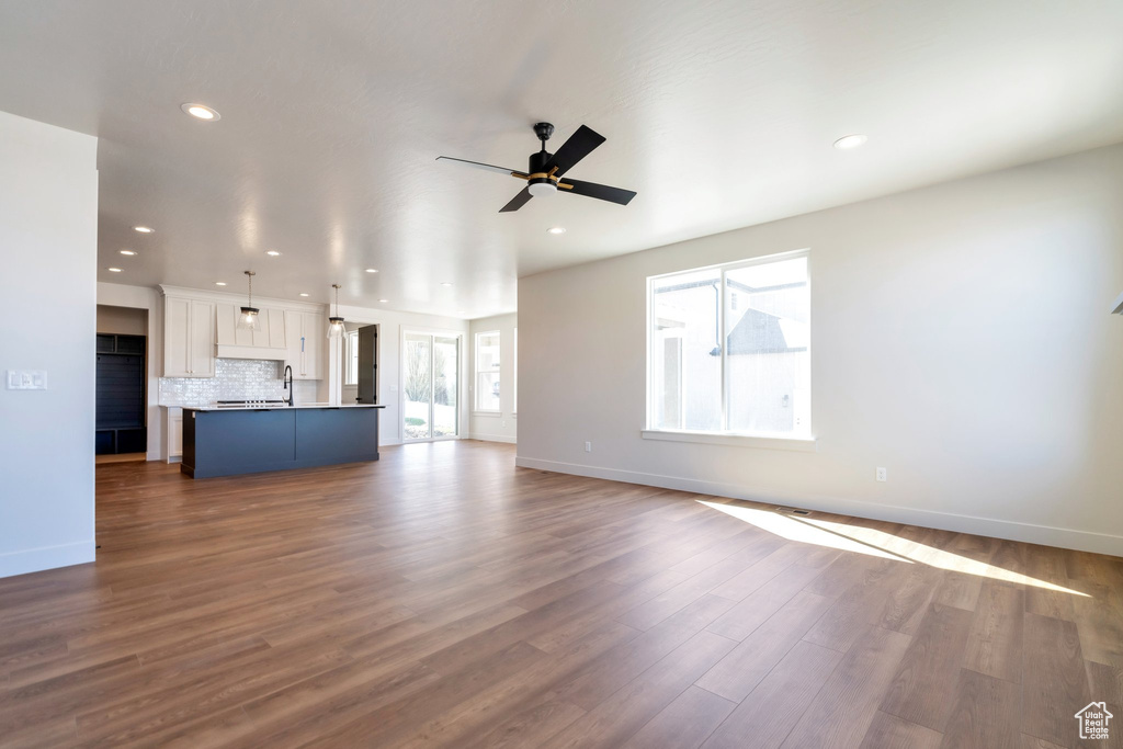 Unfurnished living room featuring dark hardwood / wood-style flooring, ceiling fan, and sink