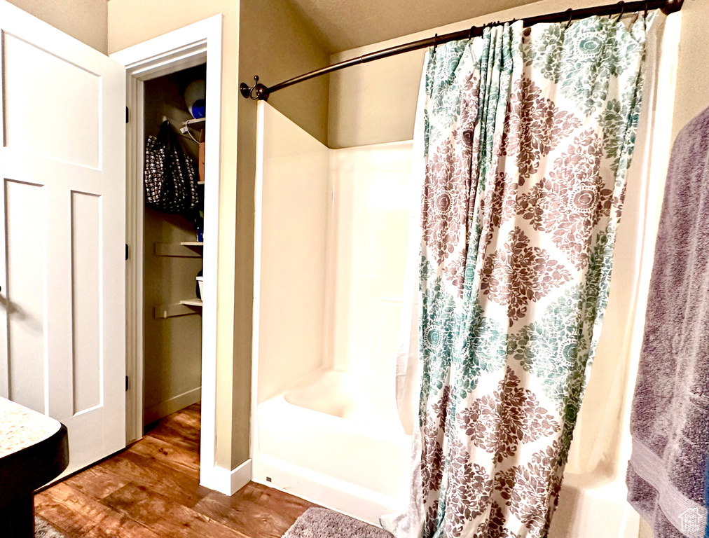 Bathroom featuring hardwood / wood-style floors and shower / tub combo with curtain