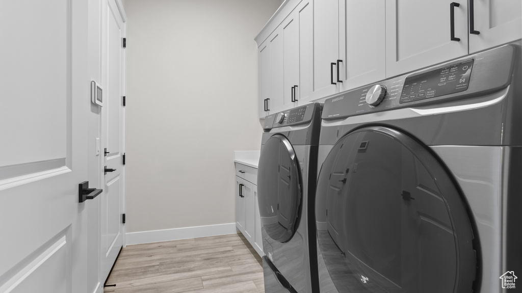 Laundry area with light hardwood / wood-style floors, cabinets, and washing machine and dryer