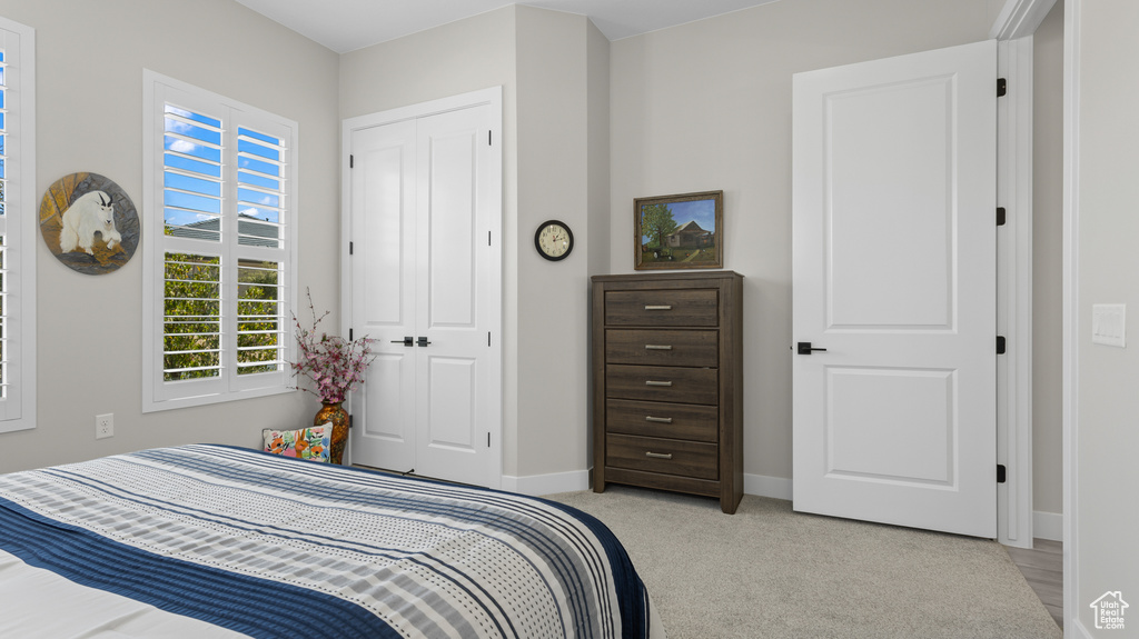Bedroom with light colored carpet and a closet