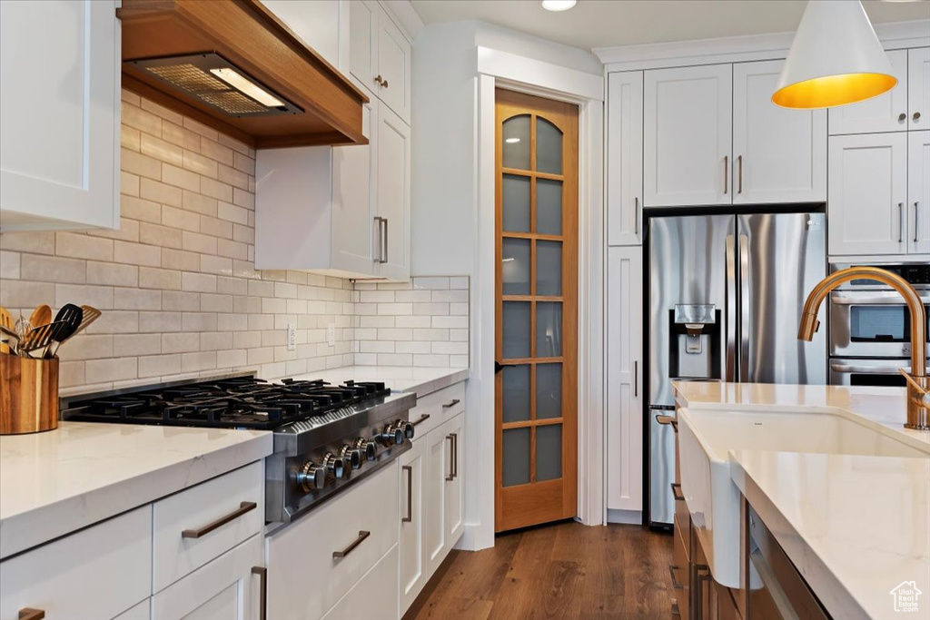Kitchen with white cabinets, light stone counters, backsplash, and dark hardwood / wood-style floors