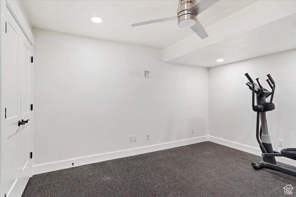 Exercise room featuring dark colored carpet and ceiling fan